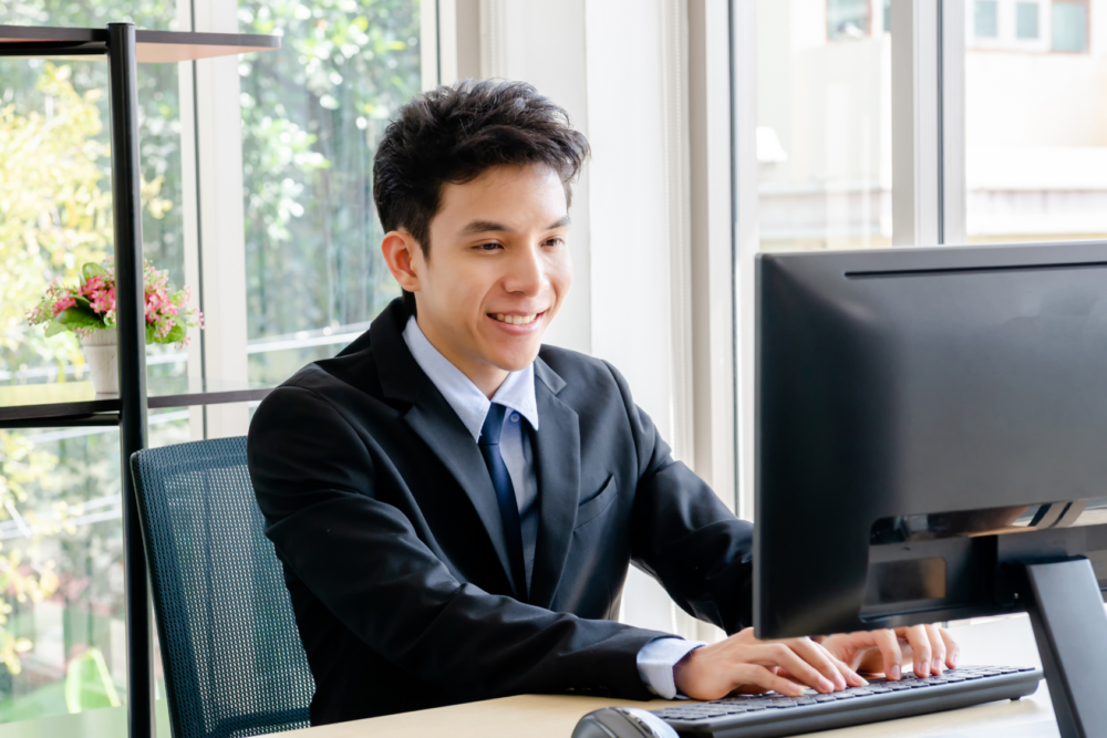 smiling businessman in office staring at his computer and typing