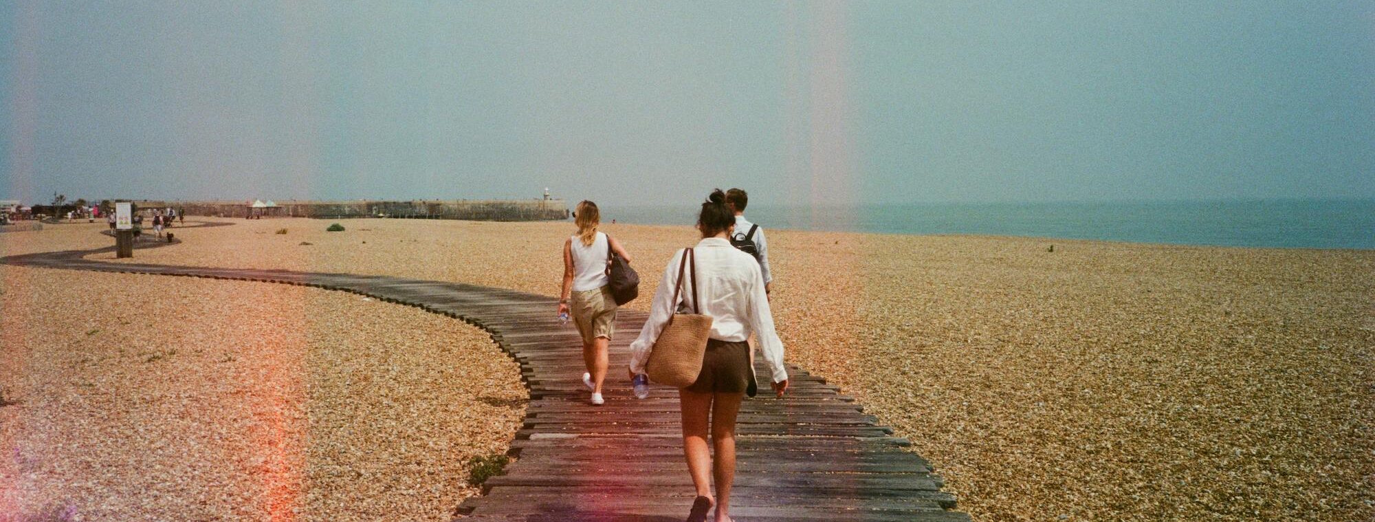 people walking down. a boardwalk in sunlight