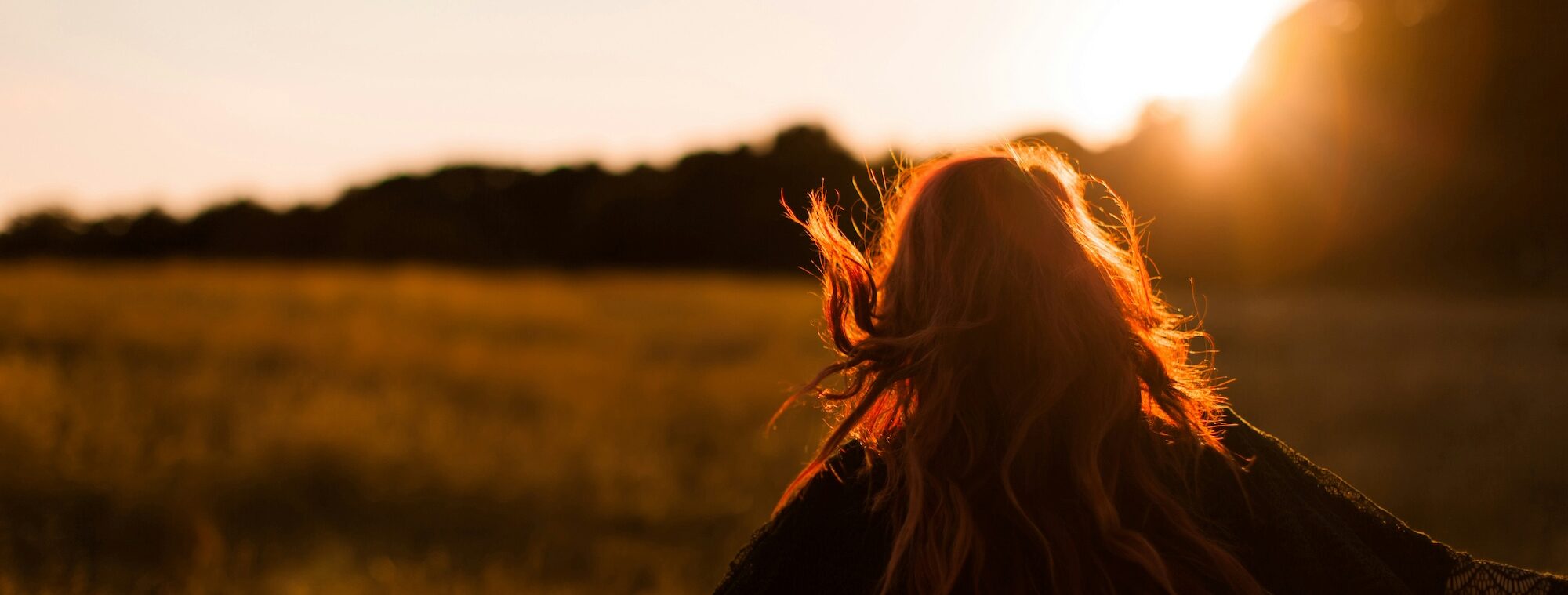 the back of a woman outside at sunset