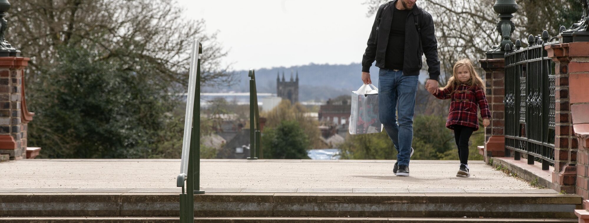A dad and daughter walking along hand in hand