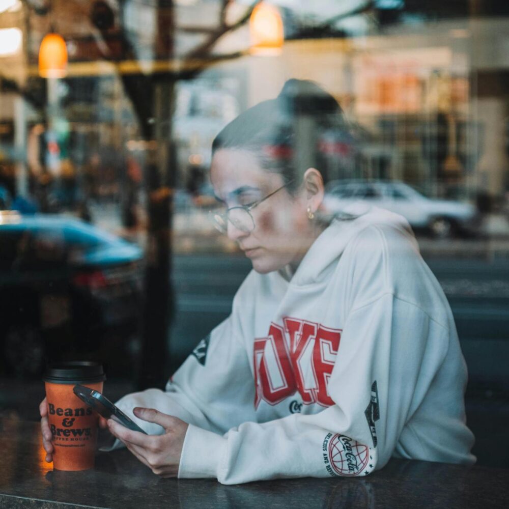 young woman on her phone behind cafe window