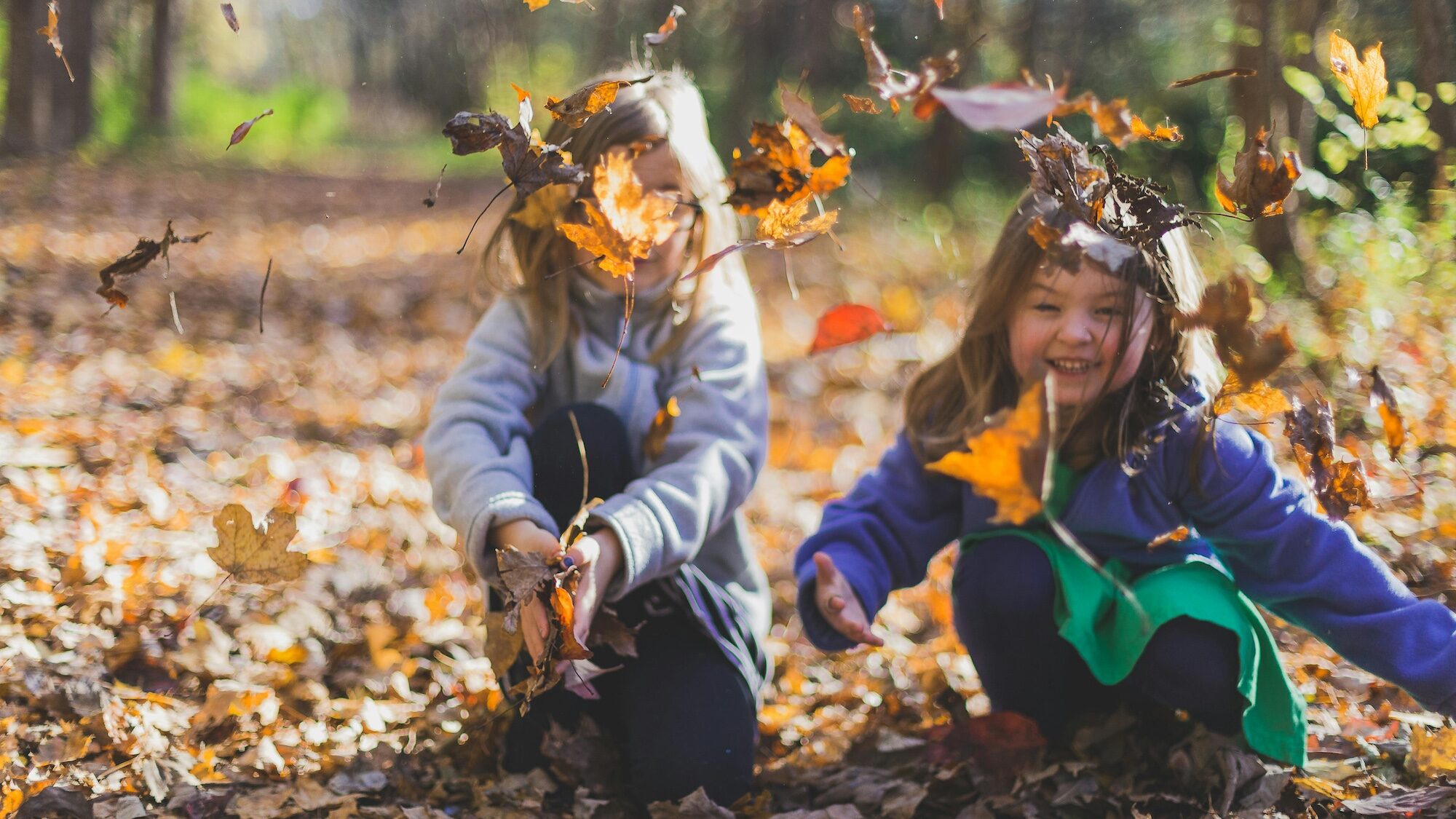 Two girls playing in leaves