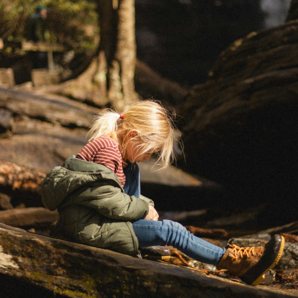 Young girl sits on a branch
