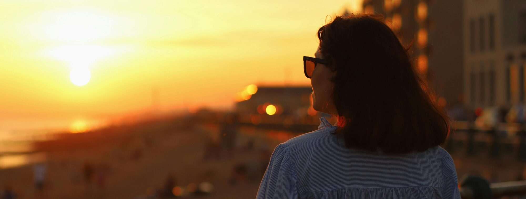 A woman on a balcony looking at the sunset