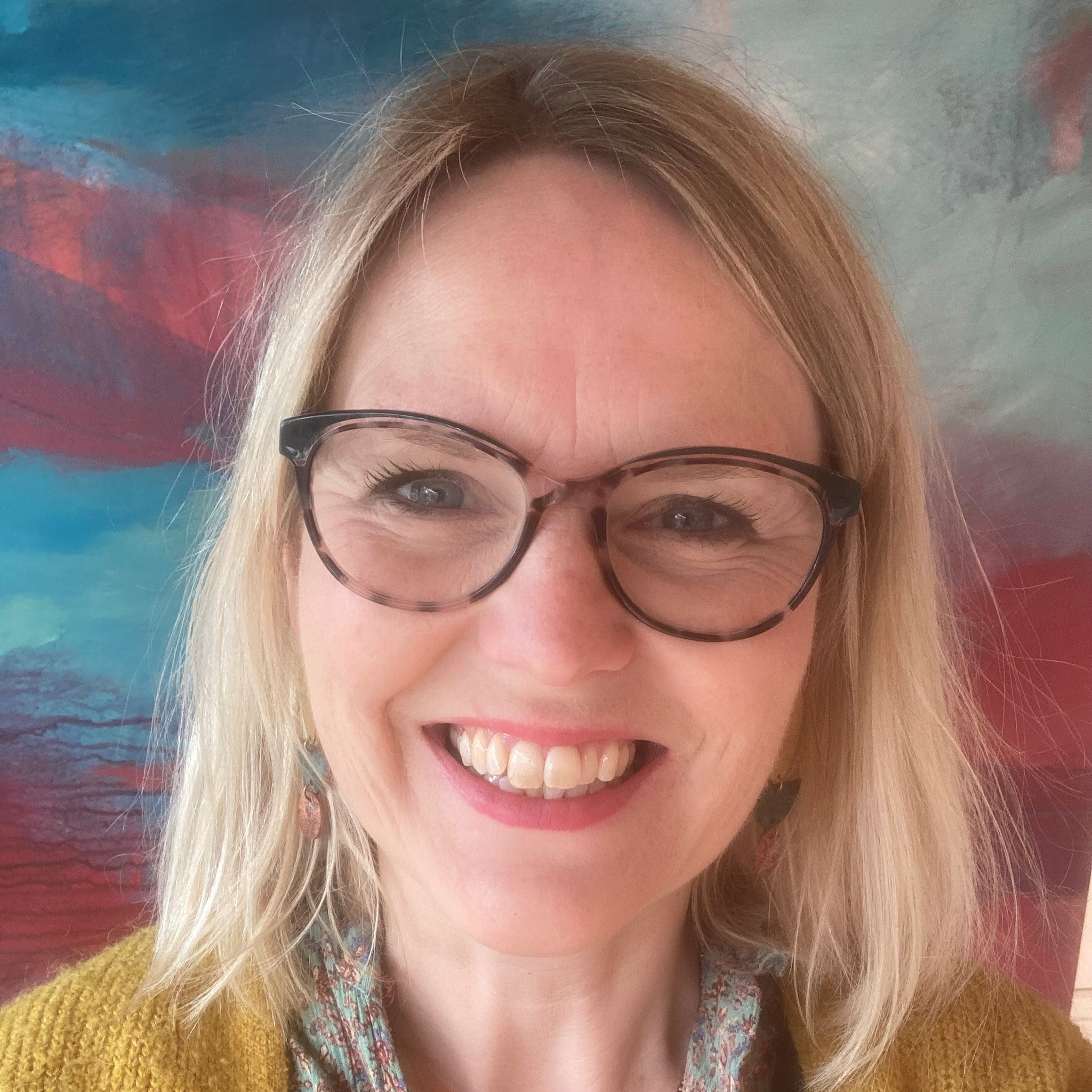 Close-up smiling woman headshot with glasses, portrait against colorful abstract background
