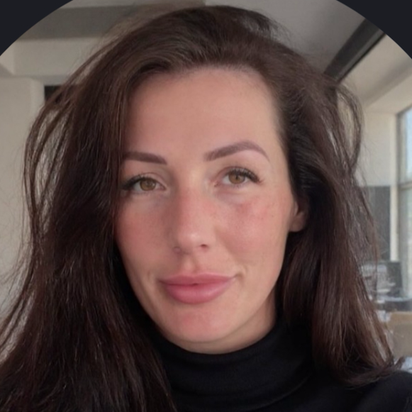 Close-up portrait of a brunette woman with natural makeup, long hair, wearing black turtleneck in bright office setting